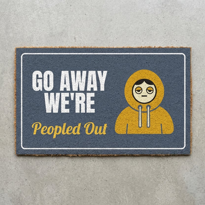 Go Away Were Peopled Out doormat 30x18 in slate grey with a tired figure in a hoodie