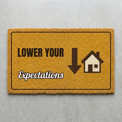 Lower Your Expectations doormat 30x18 in mustard with a down arrow and a house