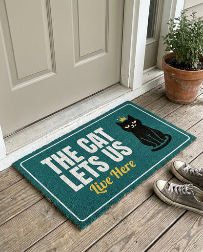 The Cat Lets Us Live Here funny cat doormat on a front porch