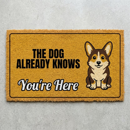 The Dog Already Knows Youre Here doormat 30x18 in mustard with an alert corgi