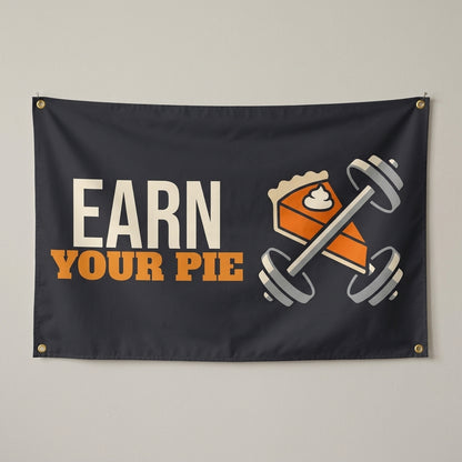 Earn Your Pie flag 3x5 in charcoal with a slice of pie and a barbell, hung on a wall
