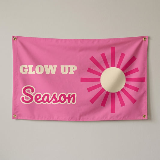 Glow Up Season flag 3x5 in pink with a hot pink sunburst, hung on a wall