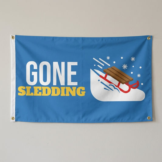 Gone Sledding flag 3x5 in blue with a wooden sled on a snowy hill, hung on a wall