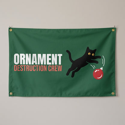 Ornament Destruction Crew flag 3x5 in dark green with a cat swatting an ornament, hung on a wall