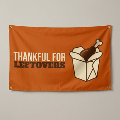 Thankful For Leftovers flag 3x5 in orange with a takeout box and turkey leg, hung on a wall