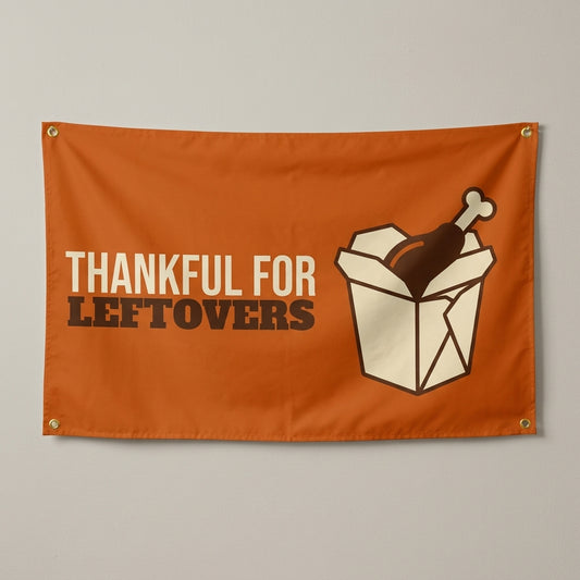 Thankful For Leftovers flag 3x5 in orange with a takeout box and turkey leg, hung on a wall