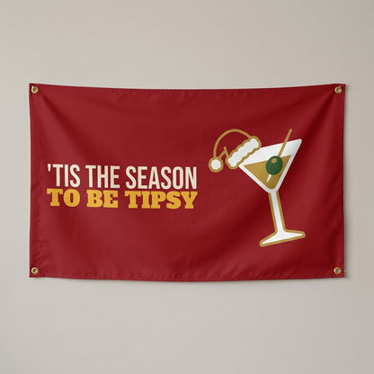 Tis The Season To Be Tipsy flag 3x5 in red with a cocktail in a tiny Santa hat, hung on a wall