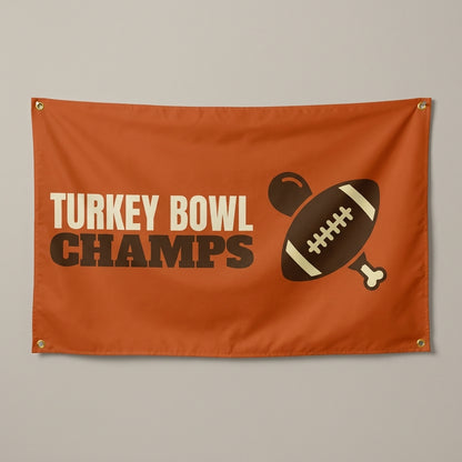 Turkey Bowl Champs flag 3x5 in orange with a football and turkey leg, hung on a wall